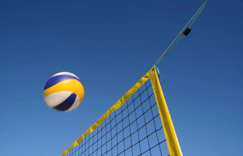 A ball floating over the net of a beach volleyball court