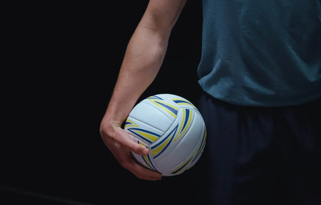 A volleyball player holding the ball in his right hand