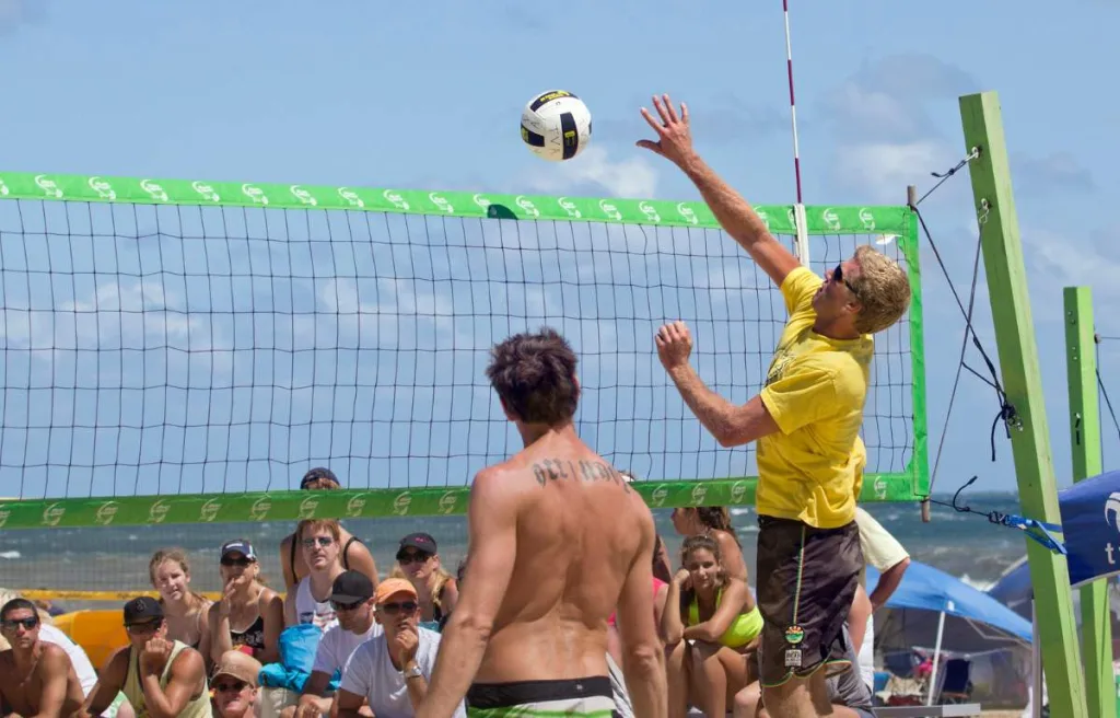 A volleyball player trying to block a serve in beach volleyball match